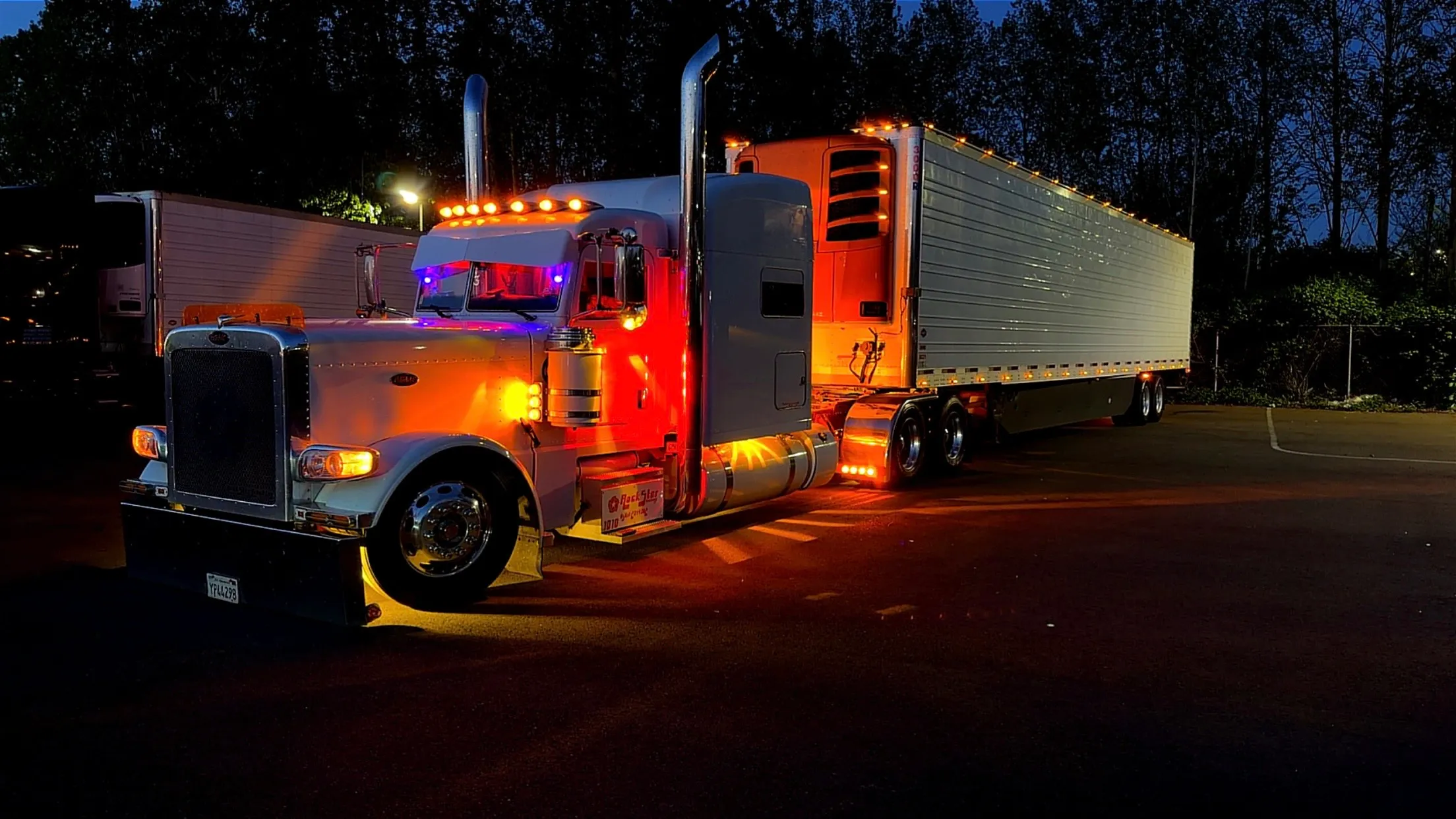 Rockstar Trucking Peterbilt with refrigerated trailer illuminated at dusk
